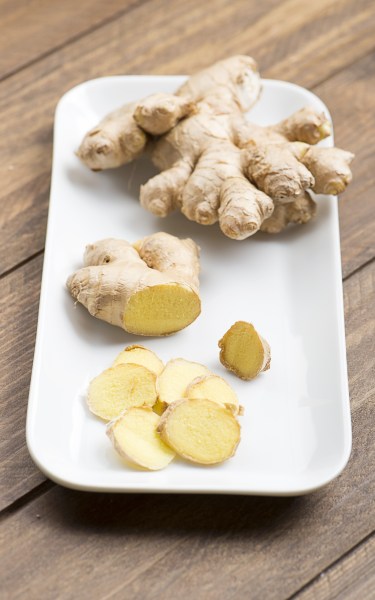 Ginger cut on a white plate, on wooden table. Food